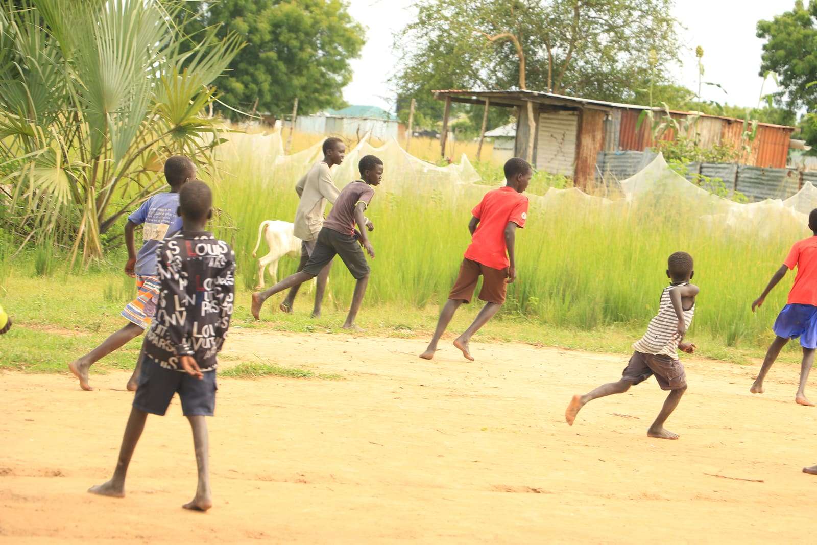 Children playing football on a dusty field