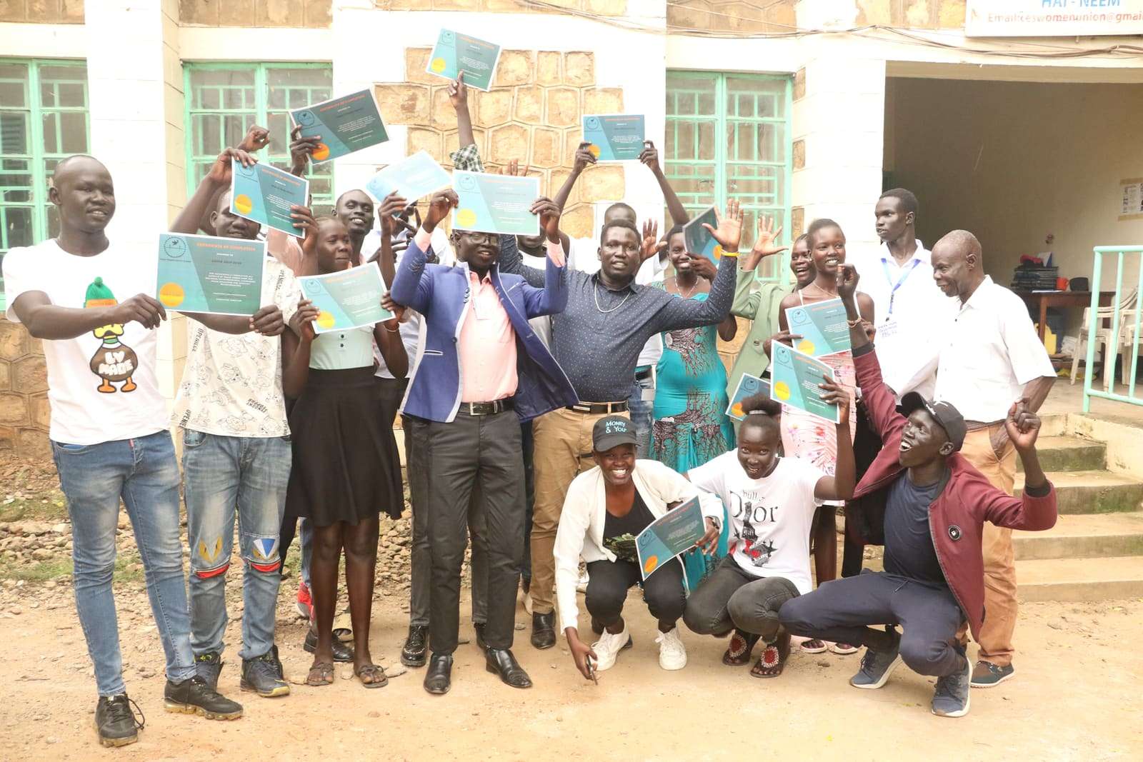 Young people and adults holding up booklets outside a building