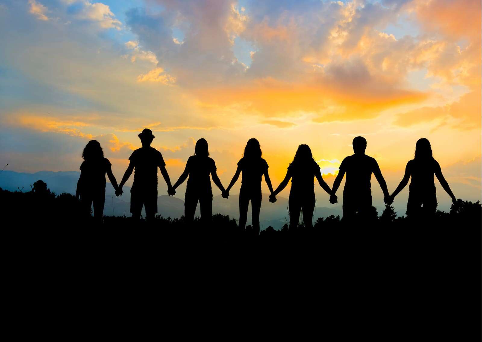 Silhouettes of people holding hands at sunset