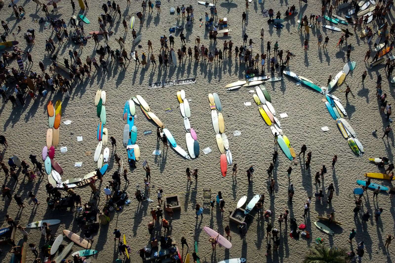 People on a beach spelling LOVE with surfboards, seen from above