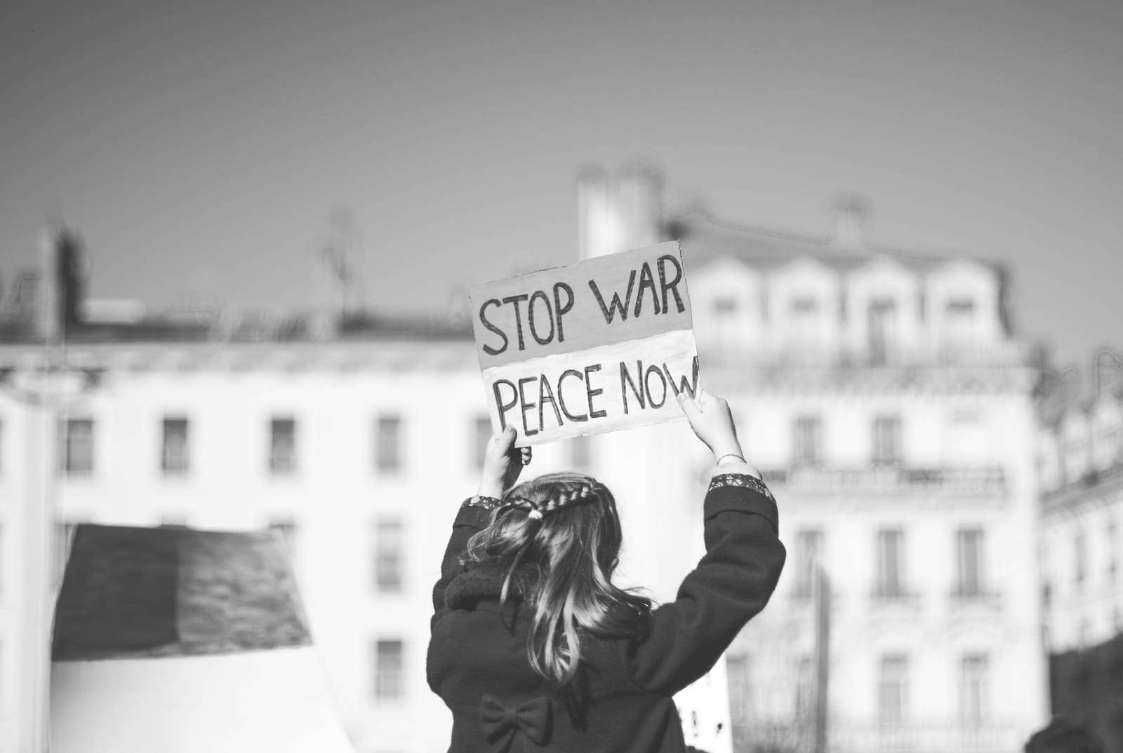 A young woman holding a “Stop war, peace now” sign