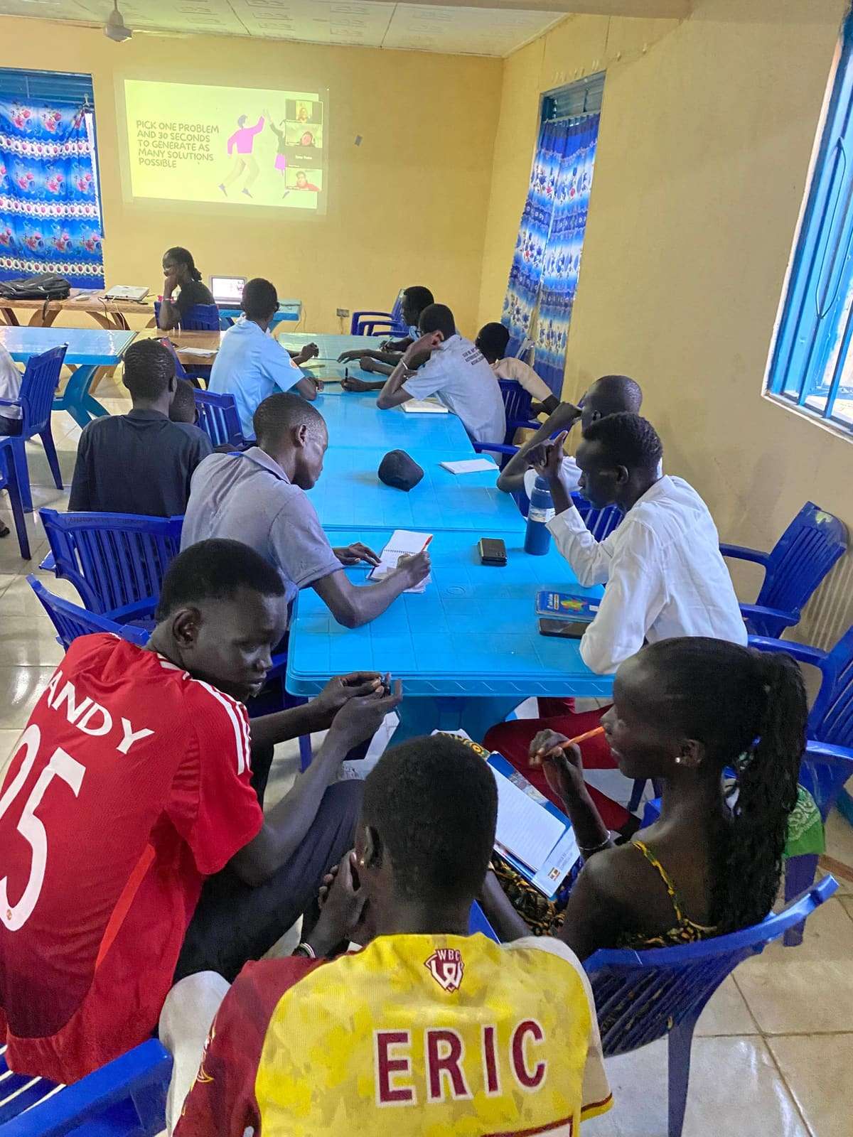 Young people at a workshop around long blue tables