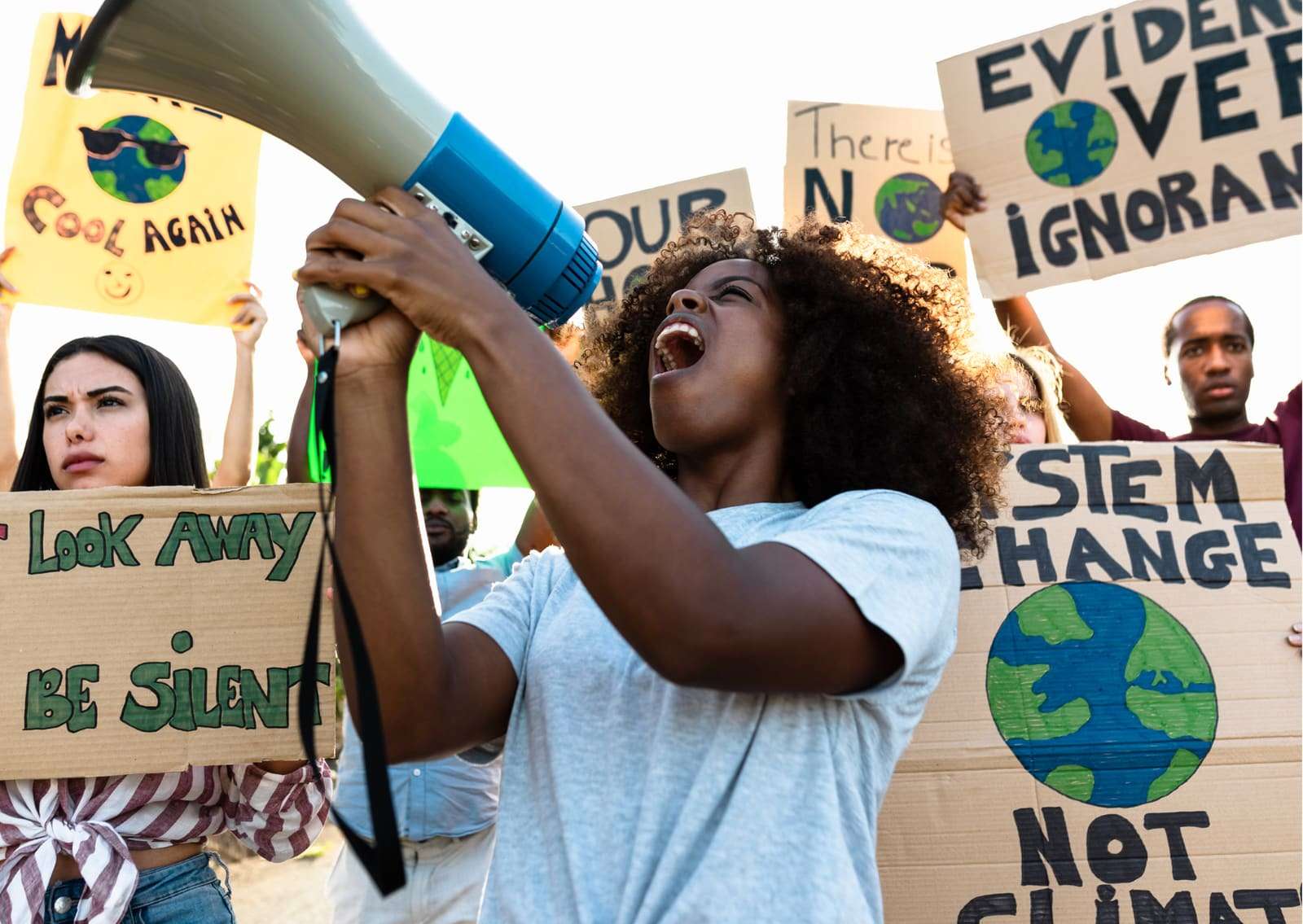 A young woman speaking through a megaphone among people holding signs